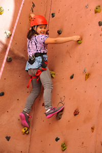Girl climbing rock wall with confidence