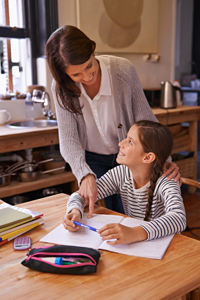 Little girl doing work at home with her mother