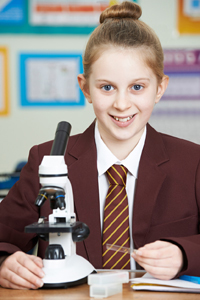 Uniformed girl at independent school using microscope