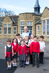 Teacher and young children standing outside primary school