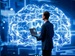 A man in a suit holding a laptop stands in front of a glowing digital brain interface, representing artificial intelligence and data-driven decision-making.