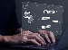 Hands typing on a laptop with a digital screen showing a ChatGPT interface, including speech bubbles, an AI brain icon, and menu options, symbolising interaction with AI.