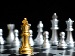 Close-up of a gold chess king on a black-and-white board with silver pieces blurred in the background, suggesting strategy, competition, and a decisive endgame.