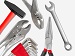 A variety of hand tools including a hammer, pliers, spanner, Allen keys, and grips laid out on a white background.