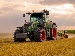 A large green tractor powered by AI technology ploughing a golden field under a cloudy sky, representing advances in smart farming and automation.