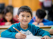 Schoolboy writing at desk in class