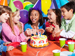 Children at birthday party with cake and balloons