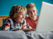 Children in bedroom writing on laptop