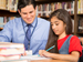 Grade 5 teacher with girl writing at desk