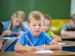 Grade 5 boy writing at school desk