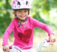 Happy little girl safely riding a bicycle
